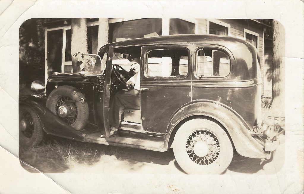 Photo of a man in a vintage auto.