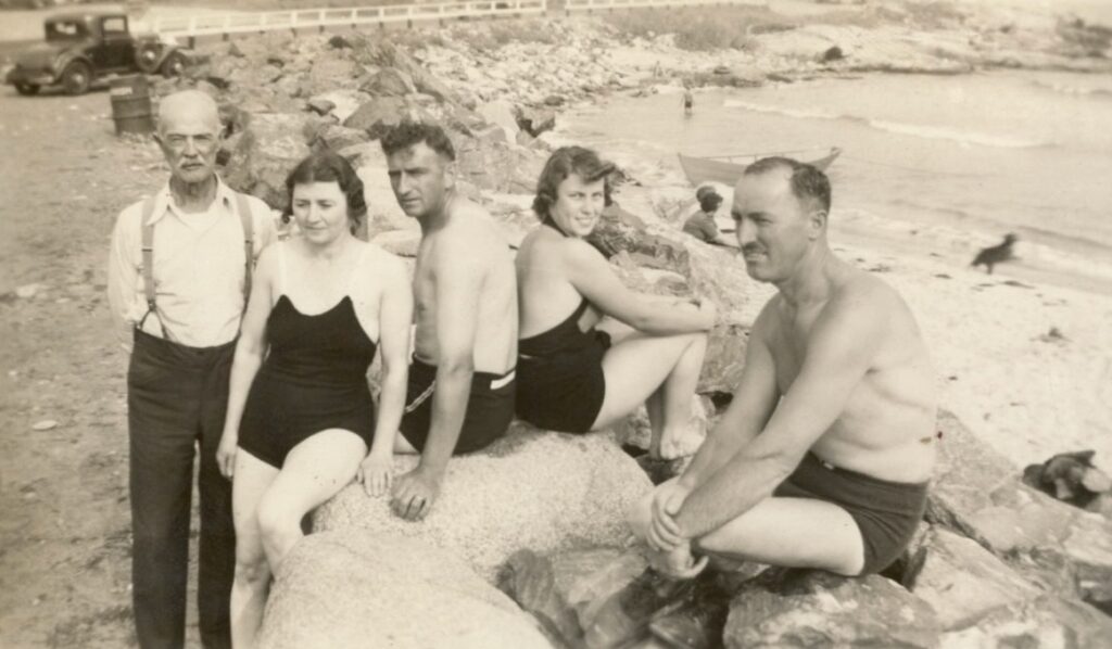 Five people at the beach - four in 1930s swiming suits. 