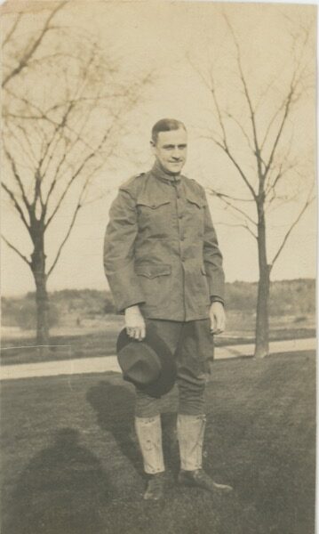 Sepia-toned full-length photograph of Philip Edward Hinkley in U.S. Army WWI uniform, holding his campaign hat, standing outdoors in May 1917.