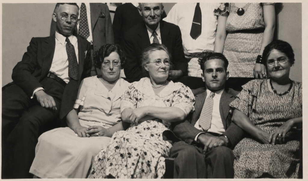 Black and white group portrait of ten family members seated and standing, 1930s