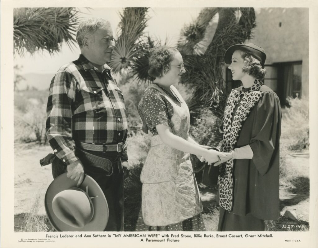 Photo — a weathered older man in a plaid shirt greeting two women outdoors among desert cacti