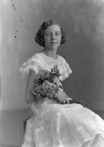 Photo of Eudora Smith, circa 1934 om a white dress & holding flowers.