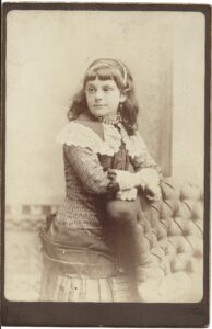 Photo of a young woman standing by a padded chair. 