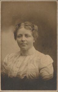 Photo of a young woman in turn of the ceentury clothing.