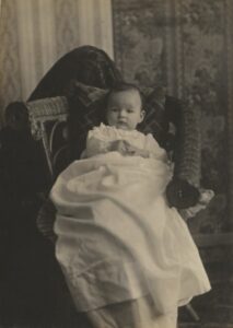 Photo of a 3-month-old baby in a long gown.