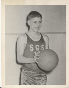 Photo of a boy holding a basketball with a jersey saying SGS.