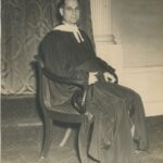Photo of a man sitting wearing a robe.