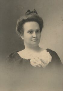 Vintage photo of a woman with a large white bow on the front of her dress.