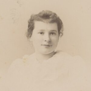 This is a photo of a young girl in a light-colored dress with puffy, full sleeves typical of the early 1890s.