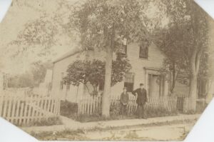 Antique photo of house with two young men.