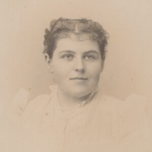This photo shows a young woman, likely between 17 and 19 years old. She is wearing a high-necked dress with a ruffled or lightly pleated collar and full shoulders, typical of the early 1890s.