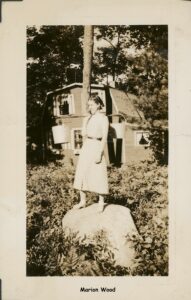 Photo of a young woman with a water carrier standing on a rock.