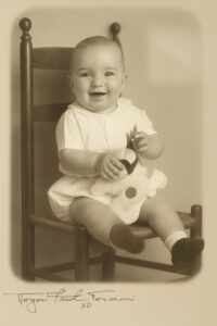 Photo of a baby, 6 to 9 months old, sitting holding a stuffed toy.