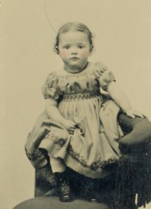 “Nellie A. (Plummer) Roberts as a child, circa 1872 tintype in decorative paper sleeve.”