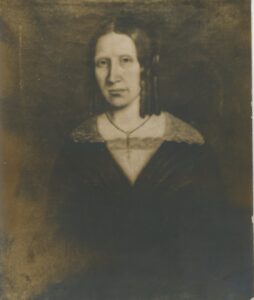 Sepia-toned photograph of an oil painting depicting a dark-haired woman with side ringlet curls wearing a dark dress with a lace collar and a cross necklace.