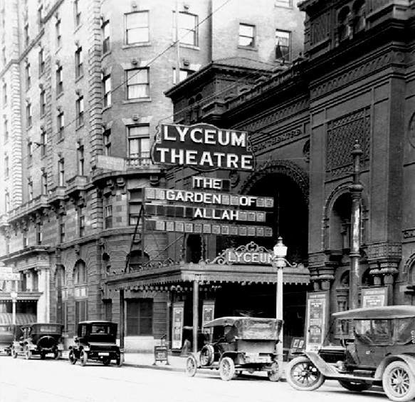 Black and white photograph of the Lyceum Theatre entrance at 36 Clinton Avenue, Rochester, New York, with a marquee reading “The Garden of Allah” and period automobiles parked at the curb